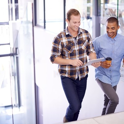 Two male colleagues taking a break from sitting at work by having a walking meeting