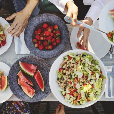 Directly above shot of friends enjoying lunch at picnic table on sunny day