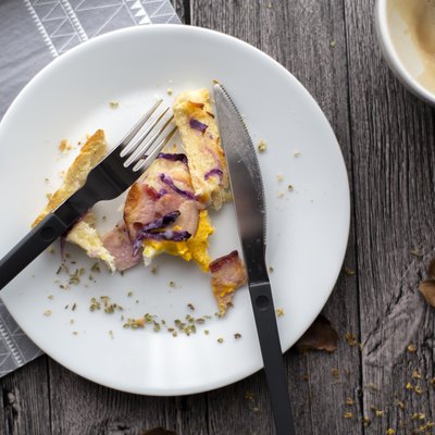 Leftover breakfast on a white plate with a knife and fork