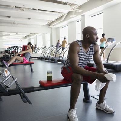 Pensive man resting on bench at gym during mindful workout