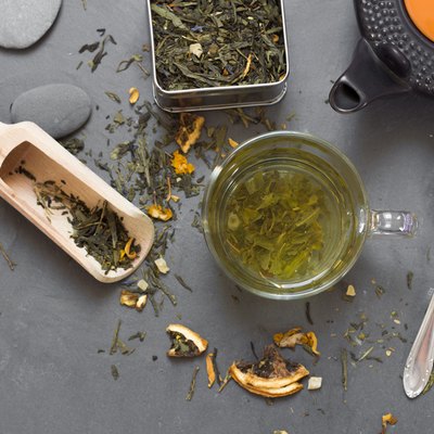 cup of green tea and dried tea on grey stone table