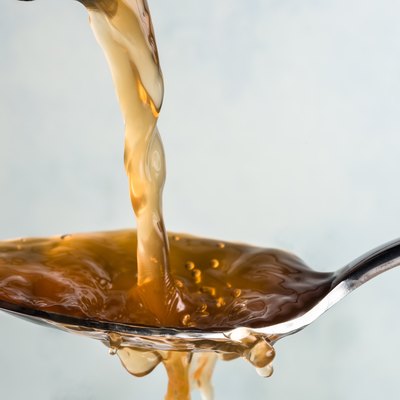 Close-Up Of Vinegar Pouring In Spoon Against White Background