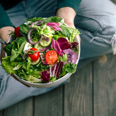 Fresh salad in hands view from above