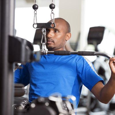 Man in a blue shirt using the lat pulldown machine at the gym