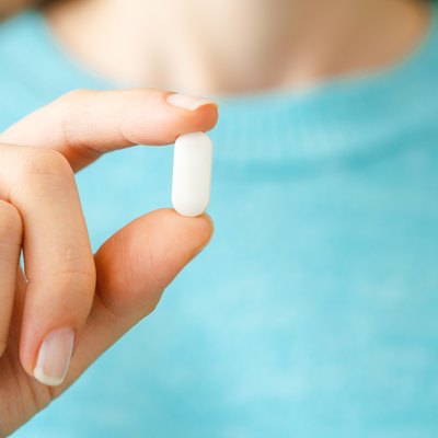 Hand holding white pill