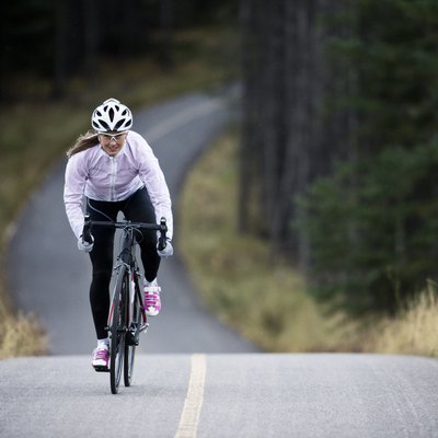 A woman rides her road bike along the Trans Canada Trail bikepath near Canmore, Alberta, Canada in the autumn.