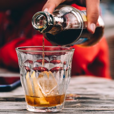 Close-Up Of Hand Pouring Drink On Table