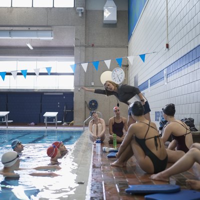 Female coach explaining stroke to swimmers in swimming pool at practice