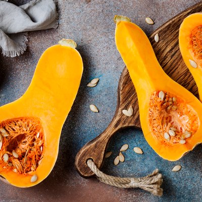 Butternut squash on wooden board over rustic background. Healthy fall cooking concept