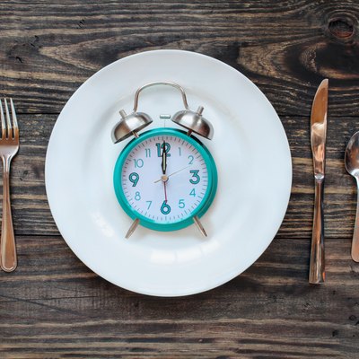 Intermittent fasting concept featuring an alarm clock on a plate