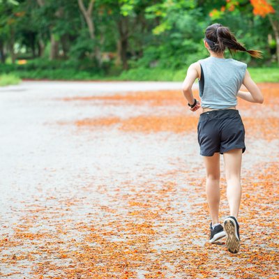Back view of young runner woman running in the park.