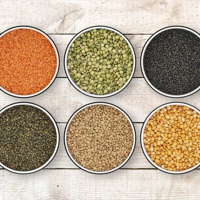 Six lentil bowls on wood background from directly above