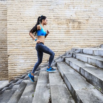 Female runner moving up on stone stairs-side view