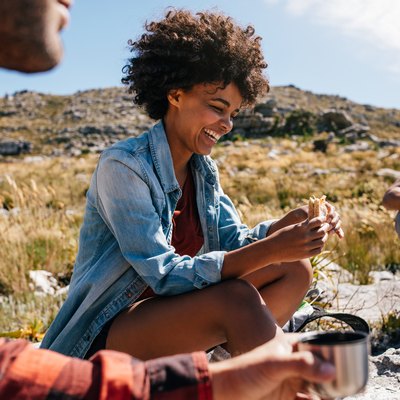 Woman with friends eating hiking snacks taking a break during hike