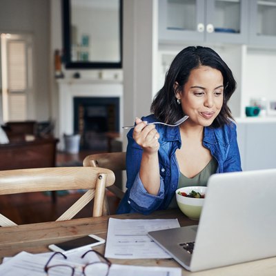 A woman eating a healthy lunch and reviewing her weight-loss program on her laptop
