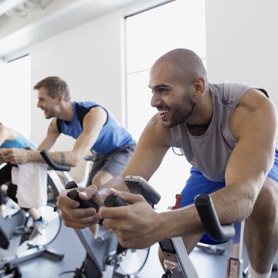 Smiling man enjoying exercise class stationary bike gym