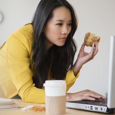 一边吃早餐一边用笔记本电脑工作的女人