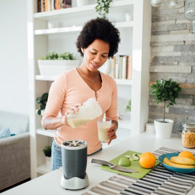 woman using blender to make a protein shake at home