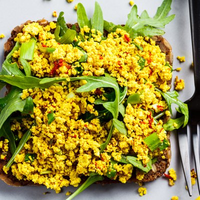 Tofu scramble toast with greens on rye bread, top view. Healthy vegan food concept.