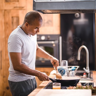 man preparing scrambled eggs for breakfast in kitchen