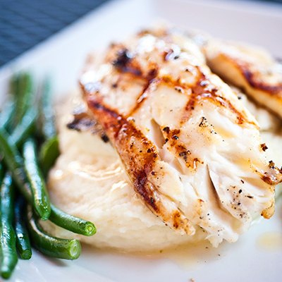 Grilled white fish on top of mashed potatoes and green beans
