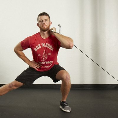 Man doing a side lunge with the cable machine at the gym
