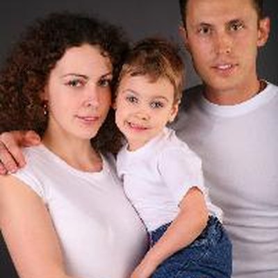 parents with child on hands on dark background