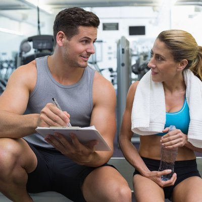 Female bodybuilder sitting with personal trainer talking