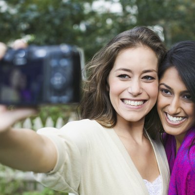 Two women taking picture of themselves with a digital camera