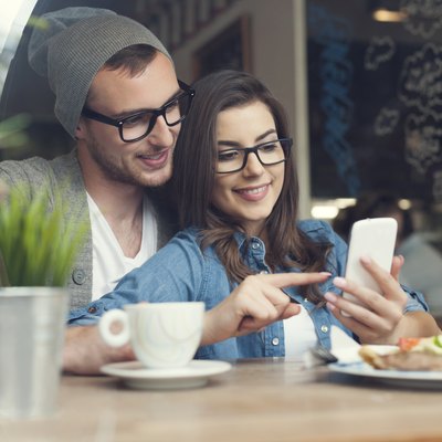 Embracing couple using mobile phone in cafe