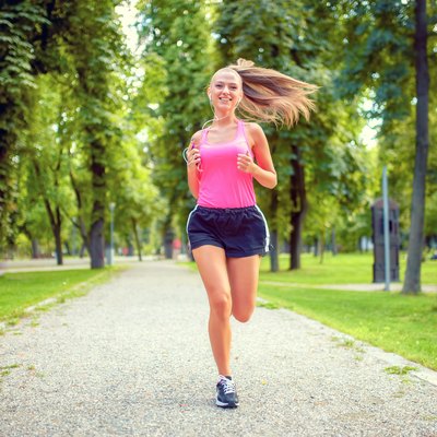 happy woman running in urban park with headphones