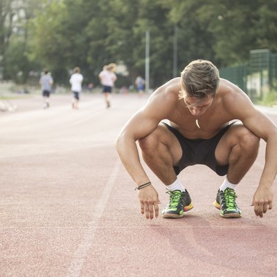 Tired sprinter at start position kneeling.
