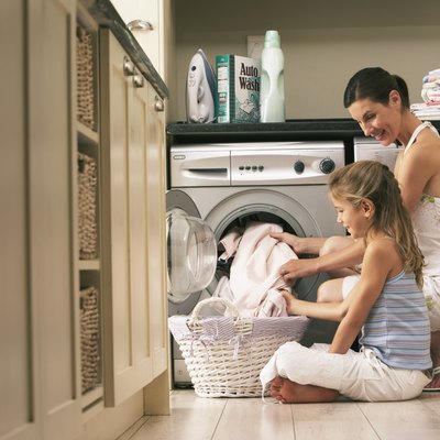 Girl (7-9) helping mother with laundry, smiling