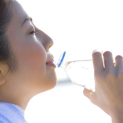 A woman drinking water outdoors.
