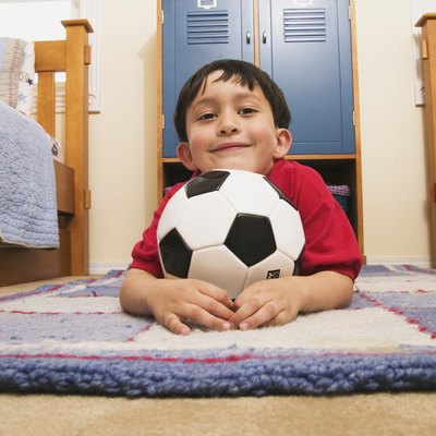 Portrait of a young boy lying on the floor holding a football