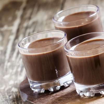 Liquid chocolate in a glass on the old wooden background