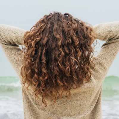 Curly brunette in a sweater on the coast