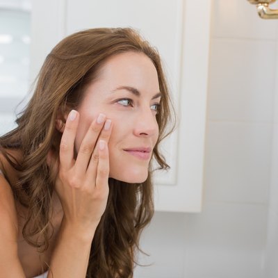 Side view of a beautiful young woman examining her face