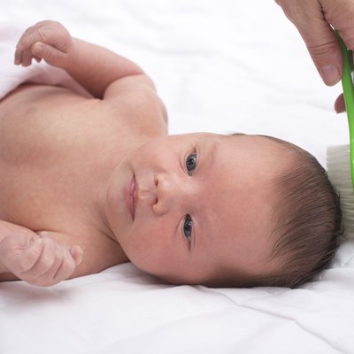 Newborn baby with mother combing