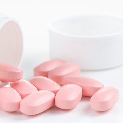 Several Pink oval pills poured out of a white bottle