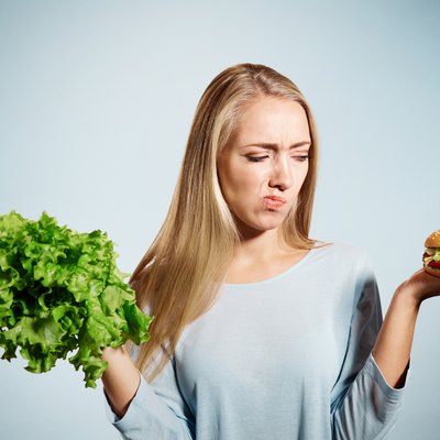 Pensive woman making decision between healthy food and fast food