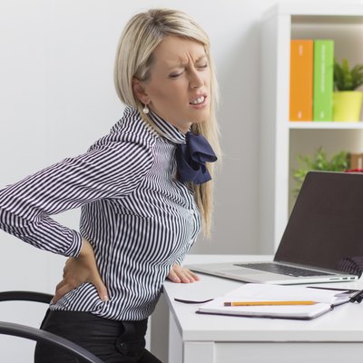 Young woman having back pain at work
