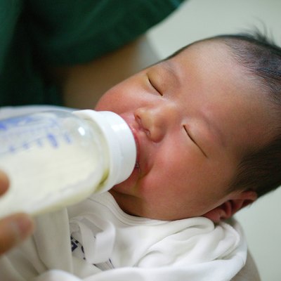 a newborn baby sucking a nursing bottle