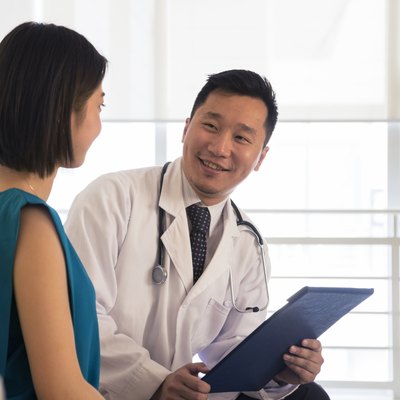 Smiling doctor sitting down and consulting patient in the hospital