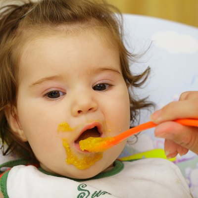 Baby being fed with food around mouth