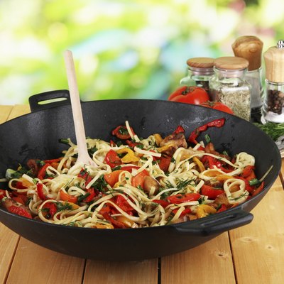 Noodles with vegetables in wok on nature background