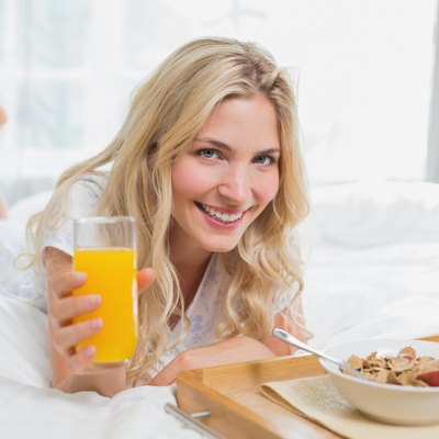 Happy young woman having breakfast in bed