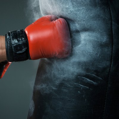 Hand of boxer and punching bag over black background