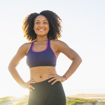 Portrait of mid adult woman, hands on hips, smiling, outdoors