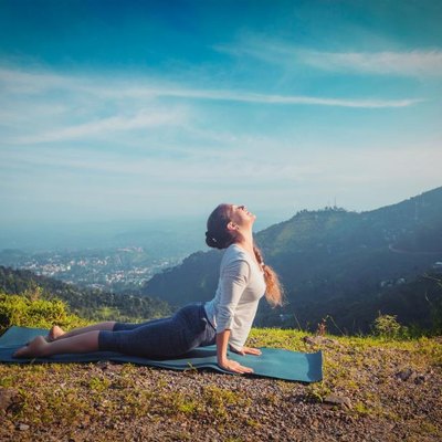 Yoga outdoors - woman practices Ashtanga Vinyasa yoga Surya Namaskar Sun Salutation asana Urdhva Mukha Svanasana - upward facing dog pose in mountains in the morning. Vintage retro effect filtered hipster style image.
